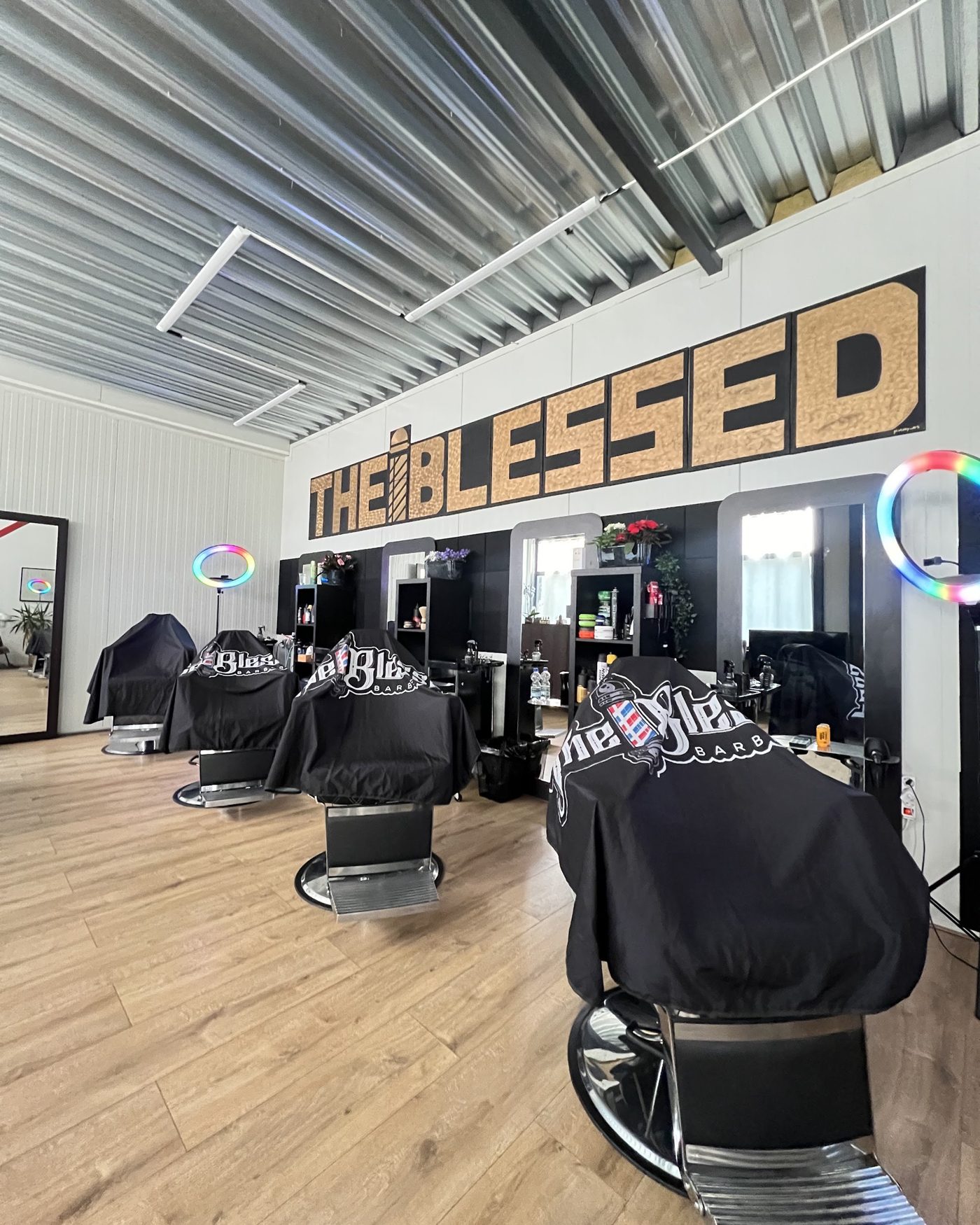 De zaak aan de Graftermeerstraat: kappersstoelen met zwarte capes onder de houten letters THE BLESSED op de muur